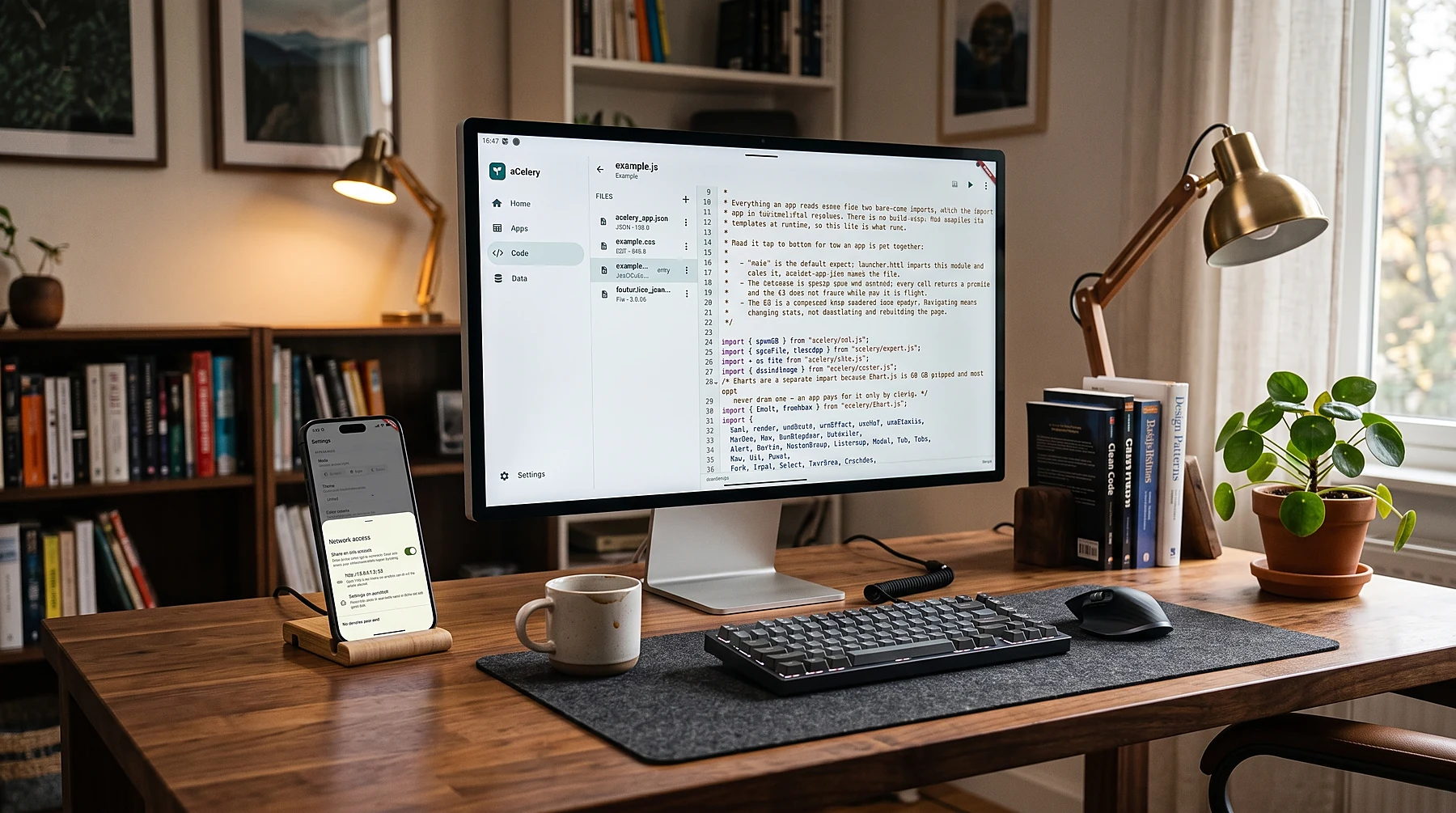 A desk with a computer editing an aCelery app in the browser while the phone beside it runs the app